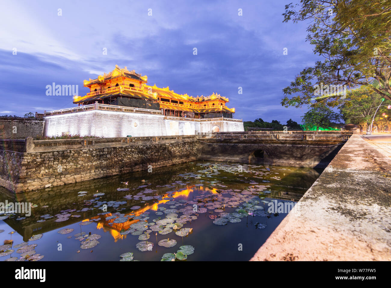 Hue, Vietnam - Junio 2019: puerta principal de la ciudad imperial prohibida púrpura al atardecer, el reflejo en el agua Foto de stock