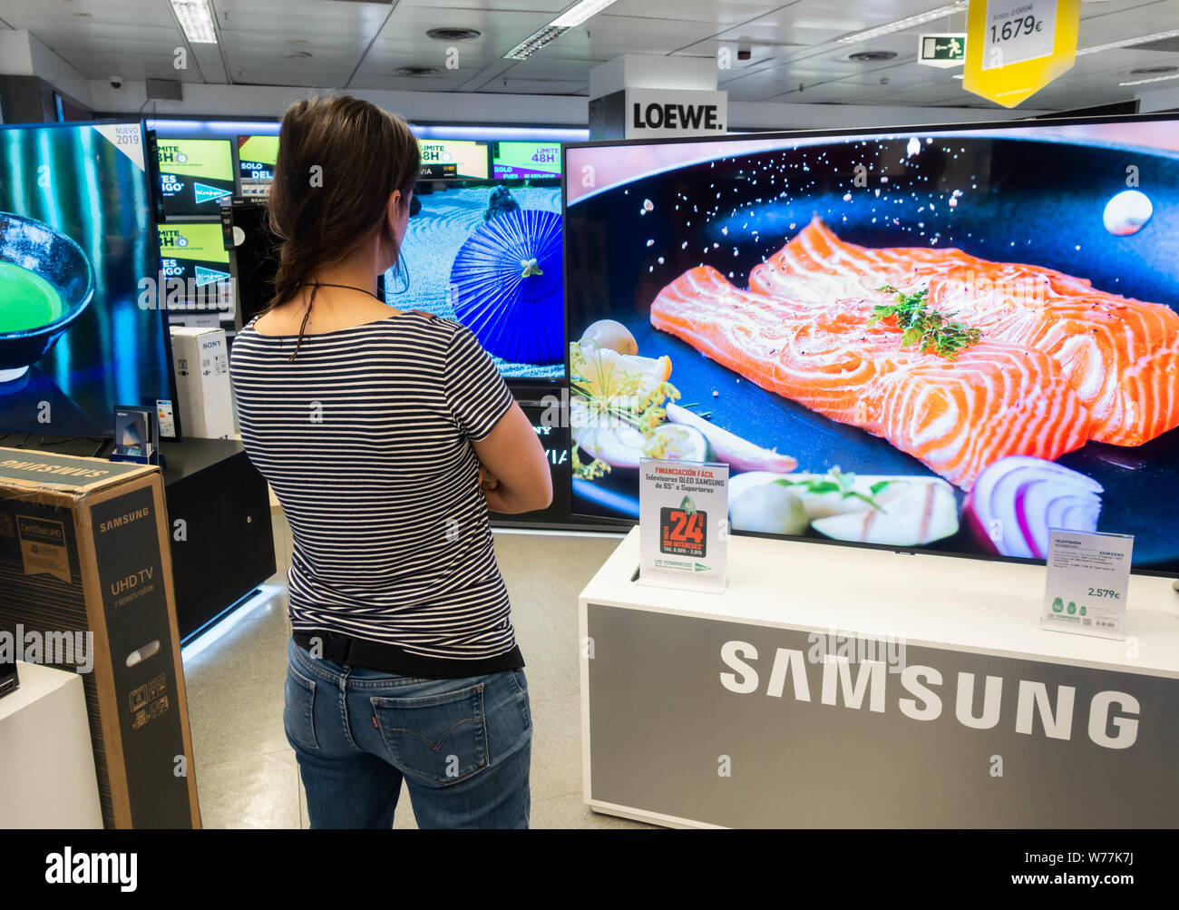 Mujer mirando su nuevo Samsung de alta definición 4k las pantallas de televisor curvo almacén eléctrico Foto de stock