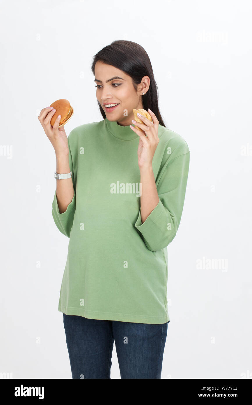 Mujer embarazada comiendo hamburguesa y samosa Foto de stock