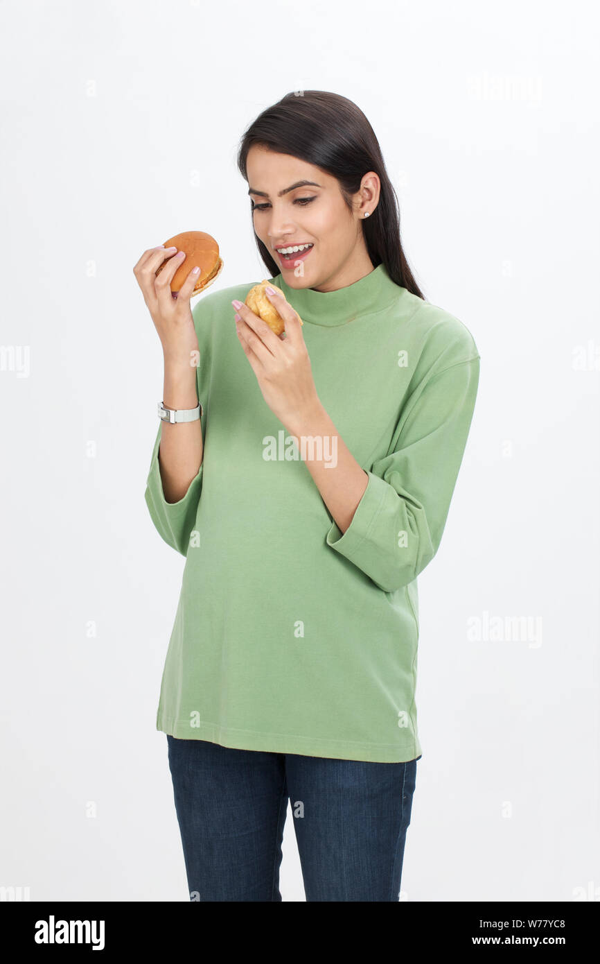 Mujer embarazada comiendo hamburguesa y samosa Foto de stock