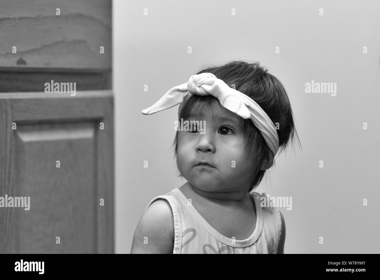 Una mujer hispana de bebé o niño pequeño, llevaba un pañuelo en la cabeza, mira hacia el lado. Foto de stock