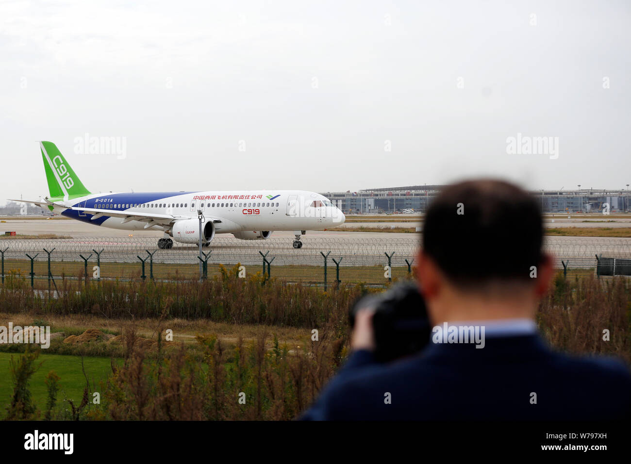 Un residente local relojes China la primera auto-desarrollado gran avión de pasajeros C919 de la COMAC (Commercial Aircraft Corporation de China) dejando Shanghai fo Foto de stock