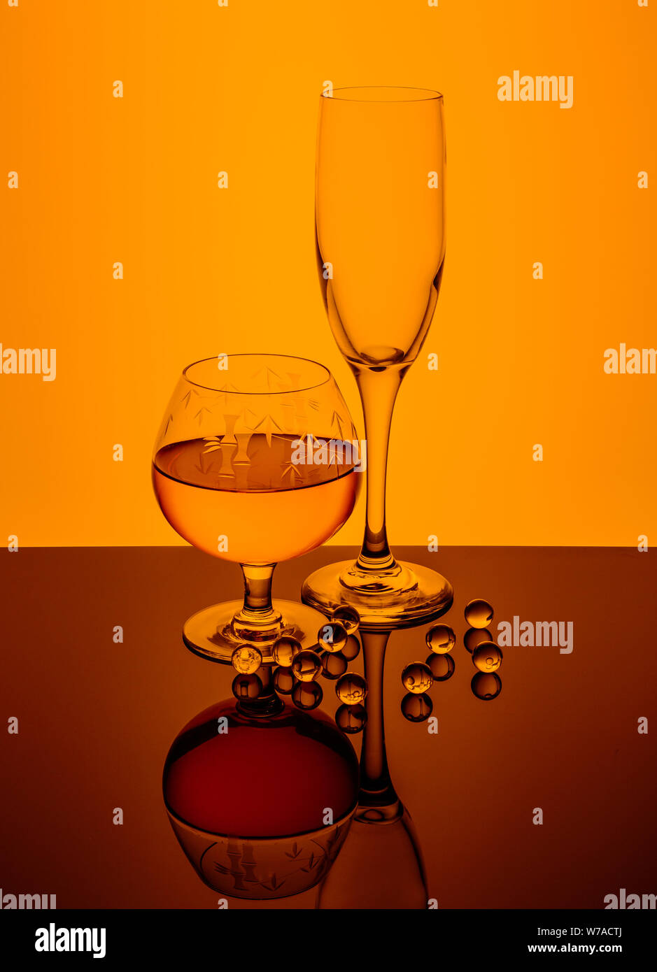 Aquí está una copa de brandy, vacía de champagne y cristal sumergidos en los mármoles de color naranja. Foto de stock