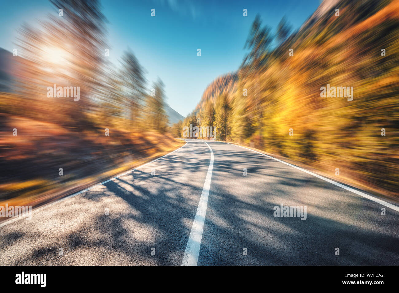 Carretera de montaña en otoño del bosque al atardecer con efecto desenfoque de movimiento Foto de stock