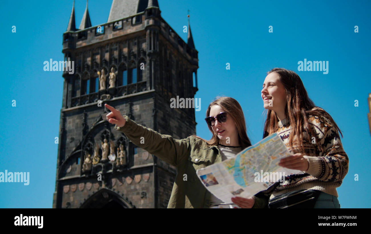 Dos jóvenes mujeres permanezca bajo la antigua torre y navigat el mapa Foto de stock