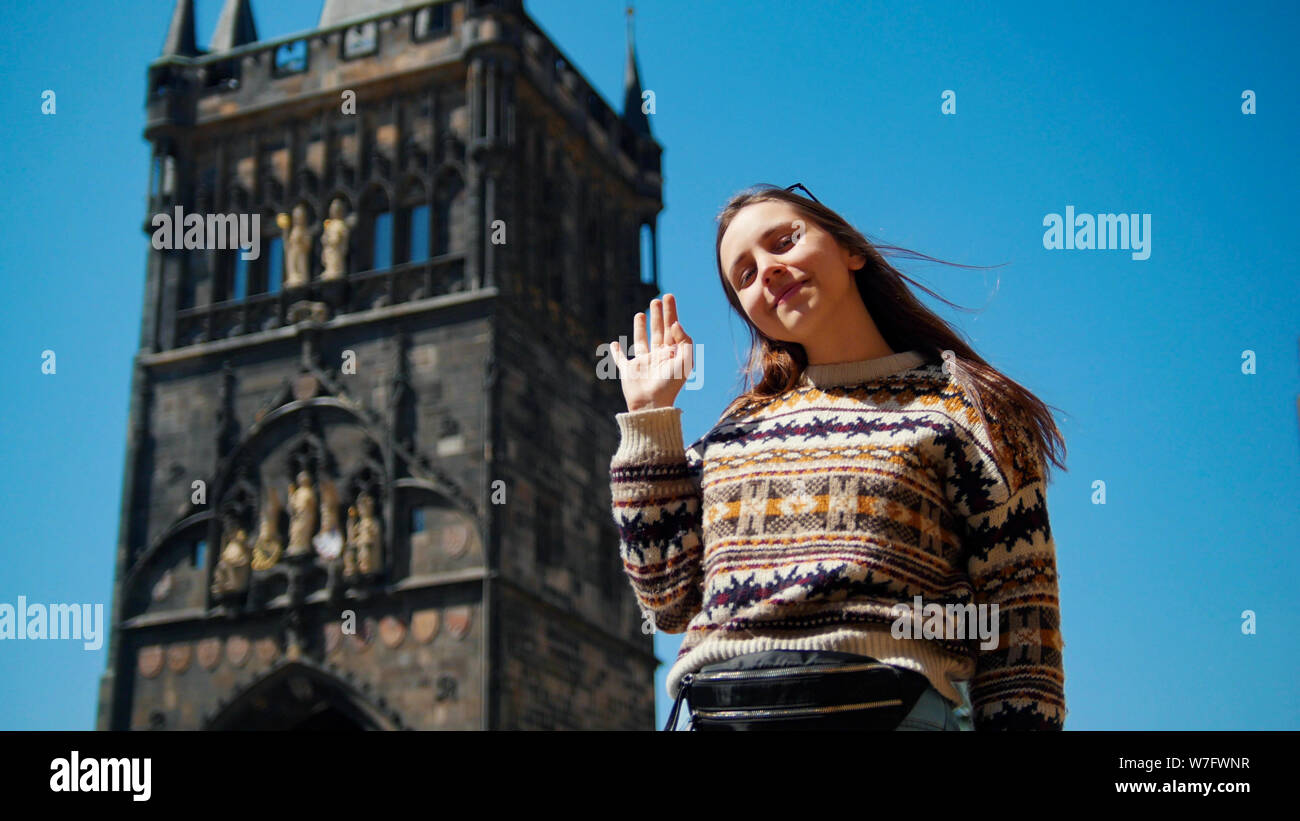 Mujer joven posando para la foto y agitando su mano en el fondo de la torre Foto de stock