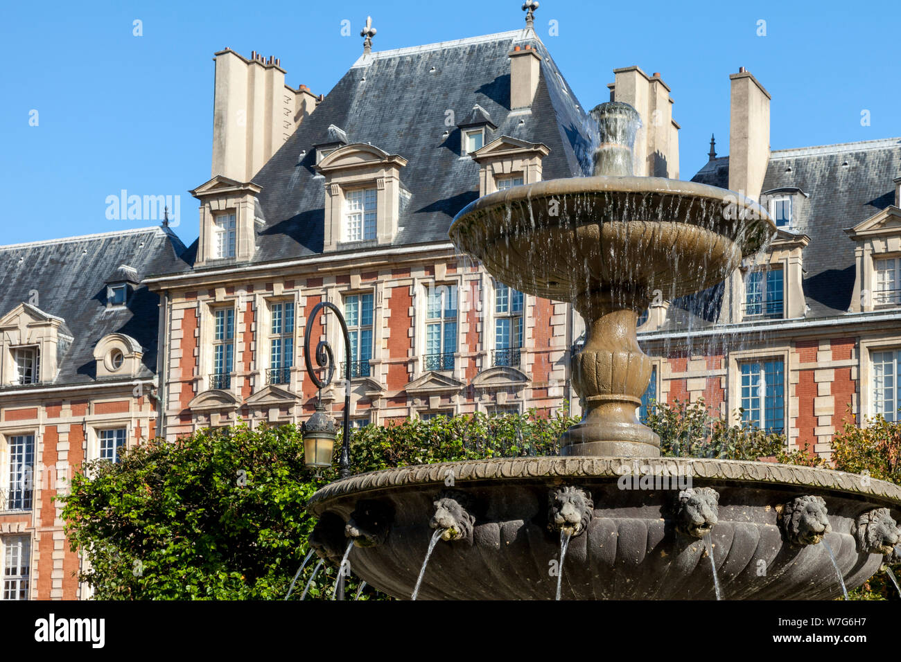 Fuente y arquitectura en Place des Vosges - la más antigua plaza pública en Paris, Ile-de-France, Francia Foto de stock