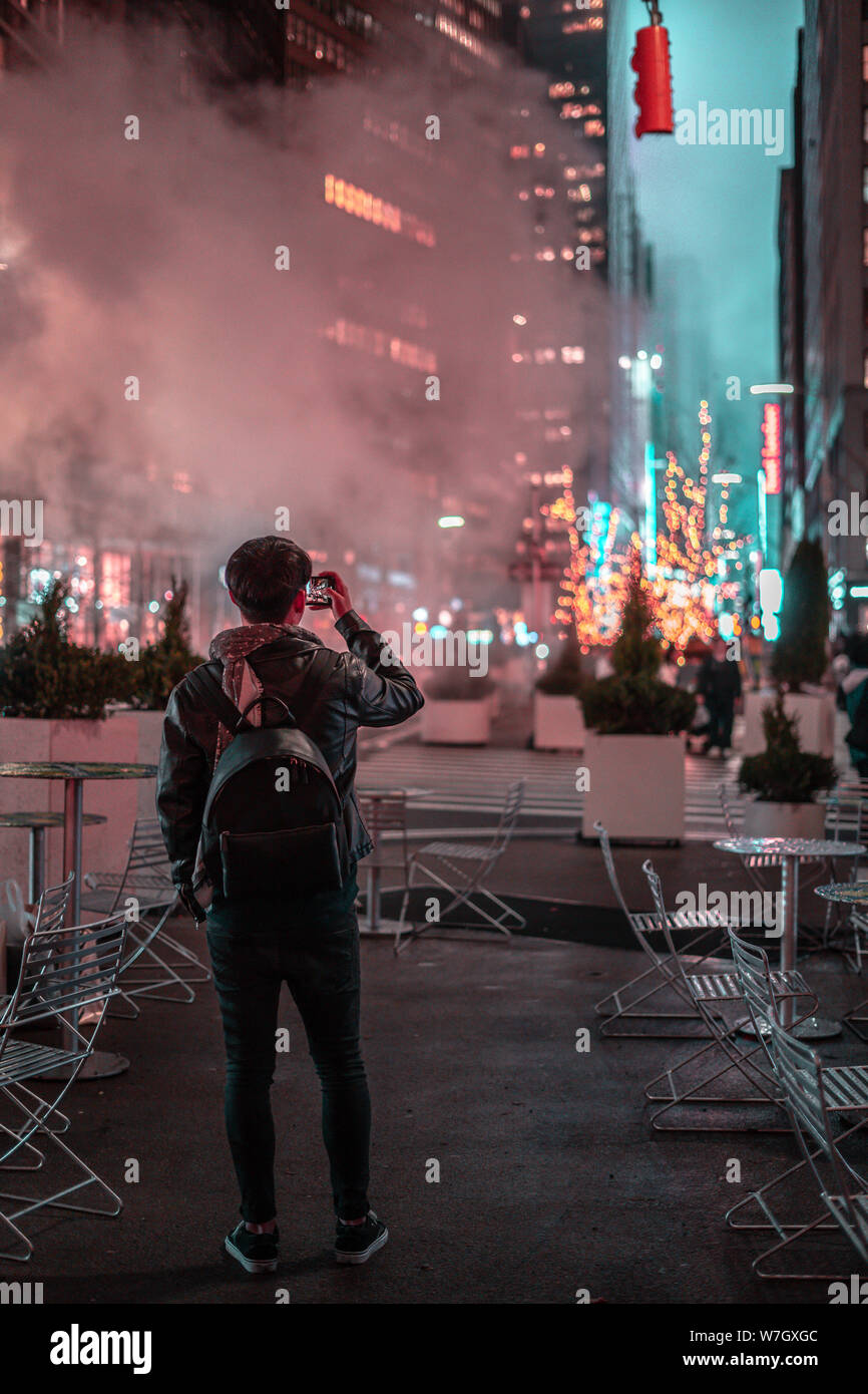 Un joven viajero tomar una fotografía con su teléfono celular en un montón  de luces de Navidad - un montón de vapor en el aire - imagen vertical  Fotografía de stock - Alamy