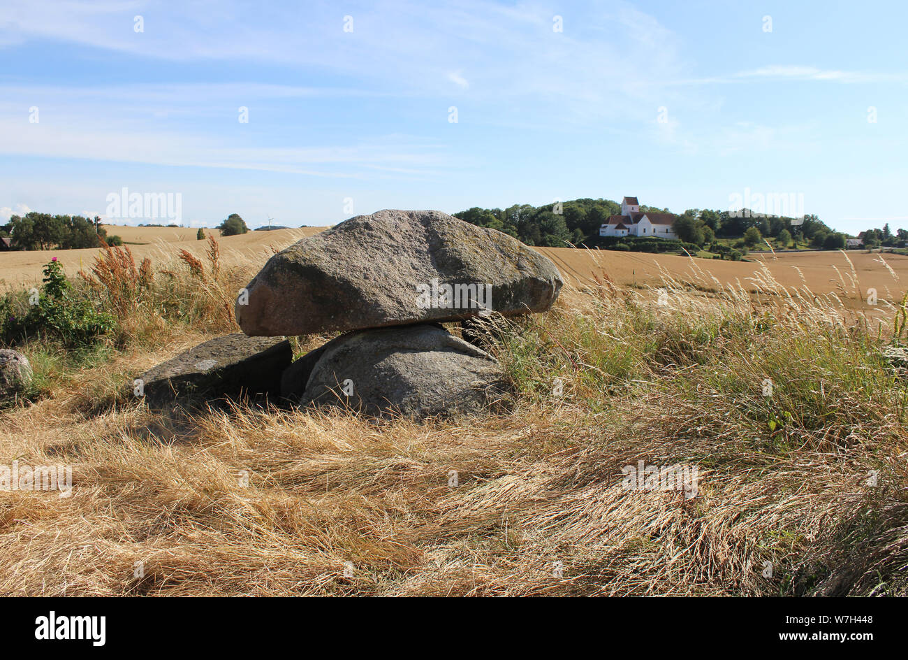 Dolmen de Kong humilla grave e Iglesia humilde en el fondo con escenas rurales circundantes. Langeland, Dinamarca. Foto de stock