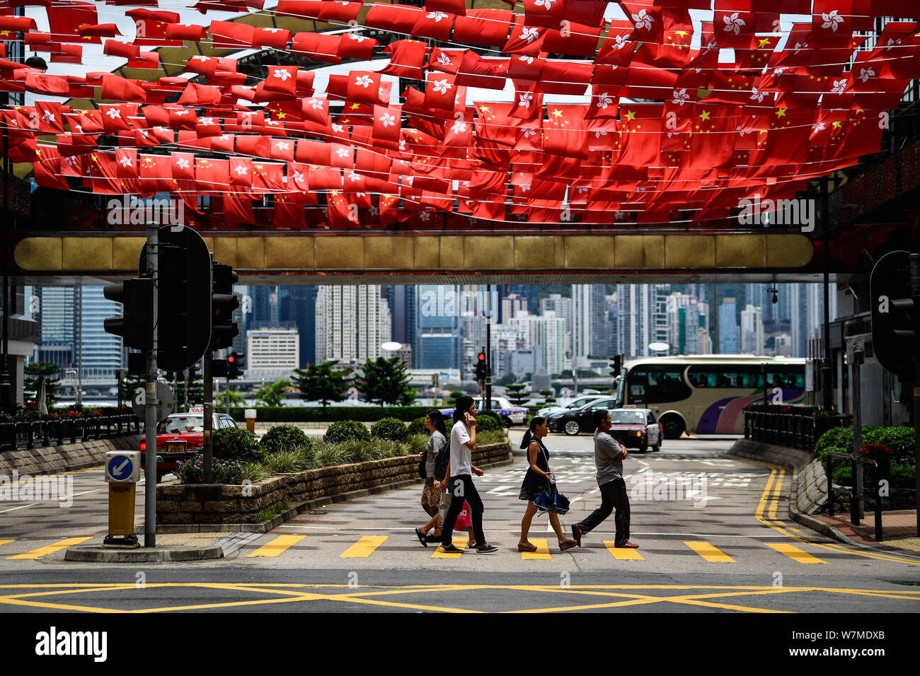Los peatones caminan bajo las banderas de China y la Región Administrativa Especial de Hong Kong de la República Popular de China para conmemorar el vigésimo decorado anniver Foto de stock