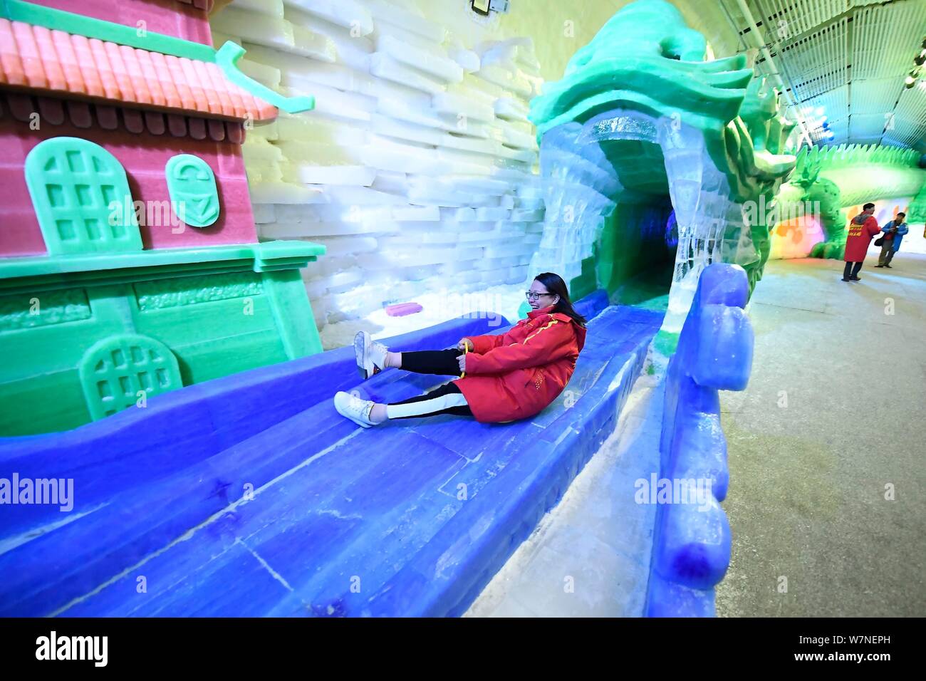 Un turista juega en una diapositiva dentro de la cueva de hielo más grande de China con coloridas luces en un día abrasador en Luya Mountain en el condado, ciudad Xinzhou Ningwu Foto de stock