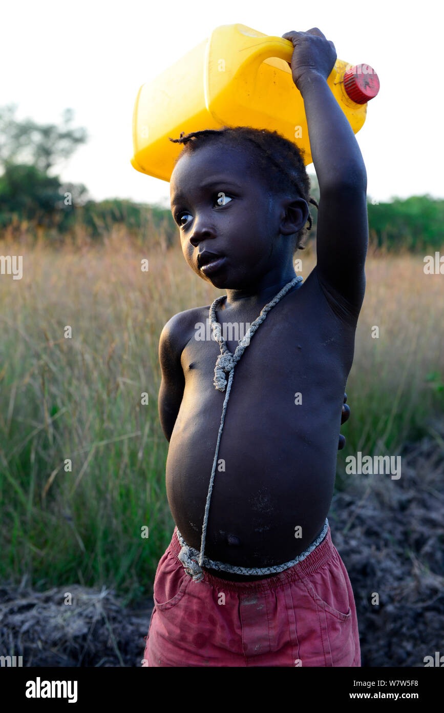 Niño llevar una botella de agua por encima de la cabeza, aldea de Eticoga, Isla de Orango, Guinea-Bissau, diciembre de 2013. Foto de stock