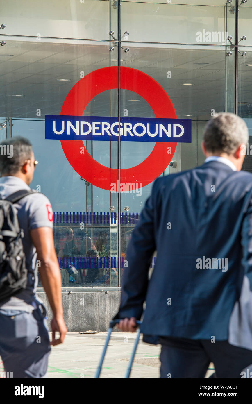 Dos hombres de negocios en sus desplazamientos por la mañana en la entrada de la estación de metro Victoria, en el centro de Londres. Foto de stock