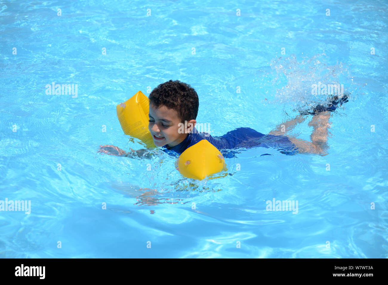 Nadador joven muchacho, nadando en el agua de la piscina azul bajo la luz solar Foto de stock