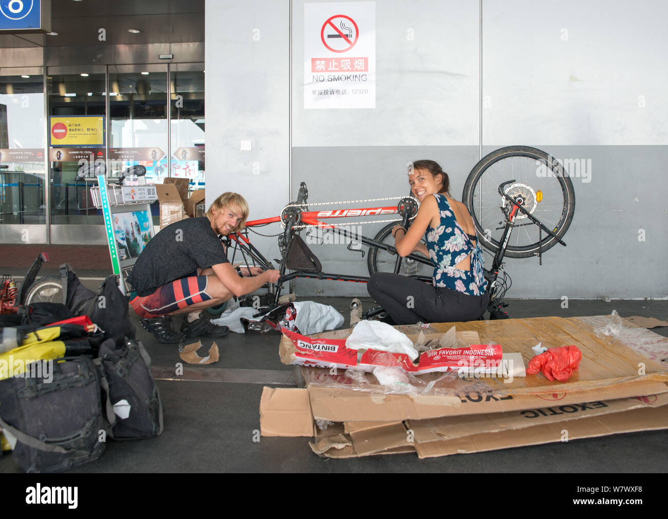 Pareja joven francés Maxime y Lise, monta una bicicleta tándem para iniciar  su viaje en bicicleta desde Pekín hasta la provincia de Yunnan en el  terminal 2 del Ser Fotografía de stock -