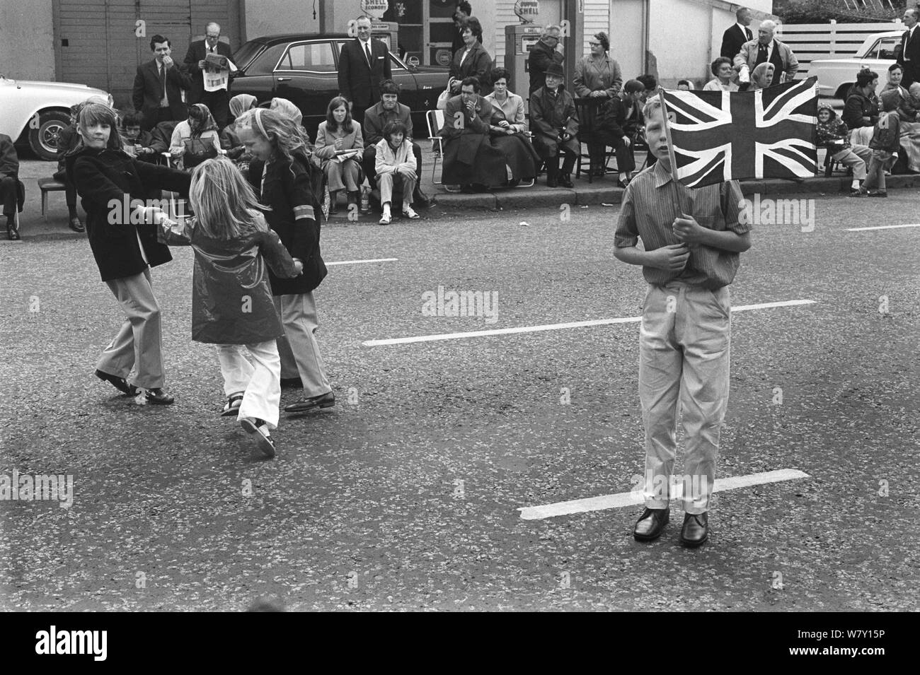 Desfile del Día Naranja de Belfast. Niños protestantes esperando que el desfile pase por su vecindario. Chicas jugando Ringa Ringa Rosie, y muchacho adolescente con banderas de Union Jack. Julio de 1970 1970 HOMER SYKES Foto de stock