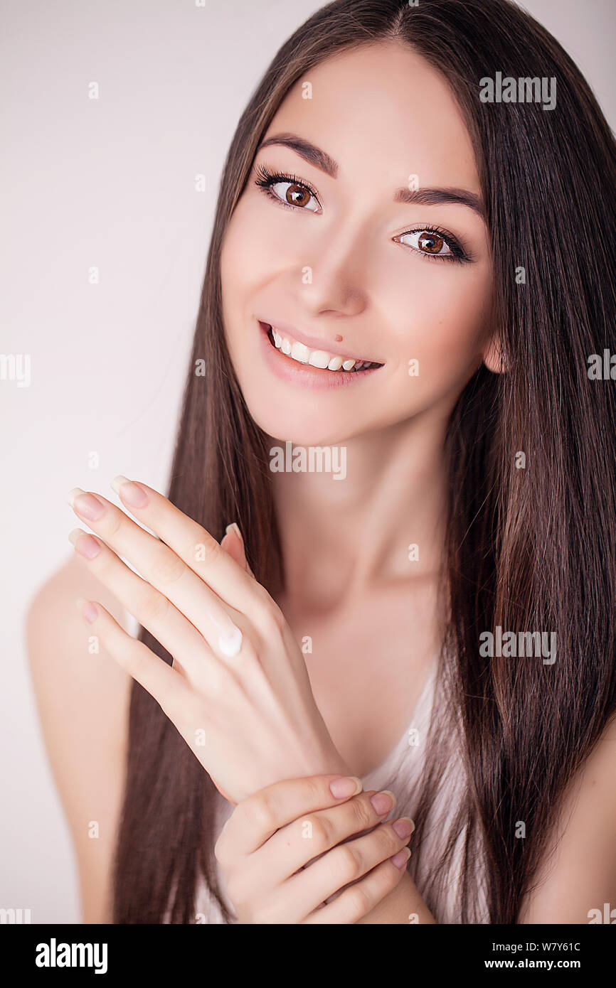 Tratamiento facial. Mujer en el Salón de belleza. Aplicar crema cosmética. Una joven y bella mujer de aplicar la crema hidratante facial. Scine cuidado de la cara y las manos Foto de stock