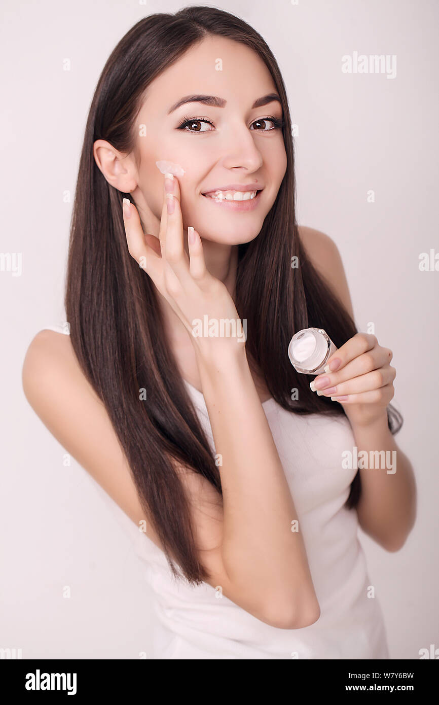 Aplicar crema cosmética. Una joven y bella mujer de aplicar la crema hidratante facial. Scine cuidado de la cara y las manos Foto de stock