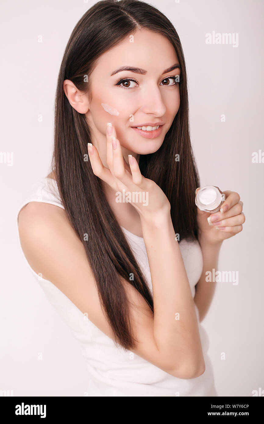 Tratamiento facial. Mujer en el Salón de belleza. Aplicar crema cosmética. Una joven y bella mujer de aplicar la crema hidratante facial. Scine cuidado de la cara y las manos Foto de stock