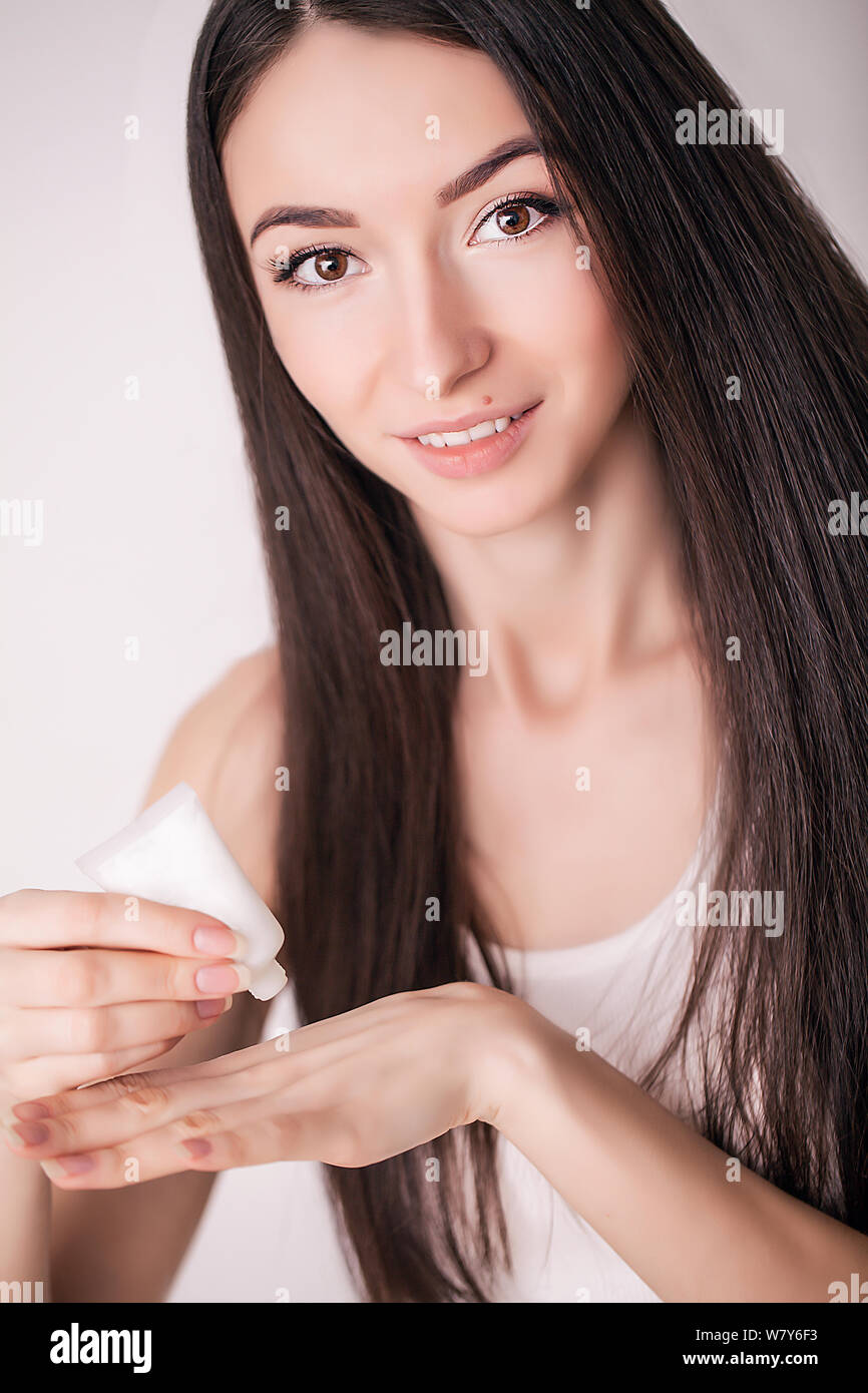 Tratamiento facial. Mujer en el Salón de belleza. Aplicar crema cosmética. Una joven y bella mujer de aplicar la crema hidratante facial. Scine cuidado de la cara y las manos Foto de stock