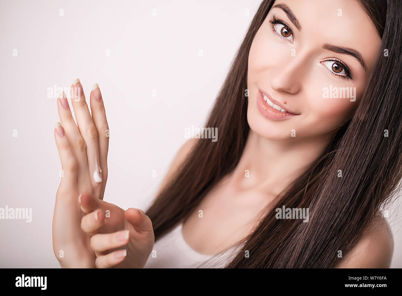 Tratamiento facial. Mujer en el Salón de belleza. Aplicar crema cosmética. Una joven y bella mujer de aplicar la crema hidratante facial. Scine cuidado de la cara y las manos Foto de stock