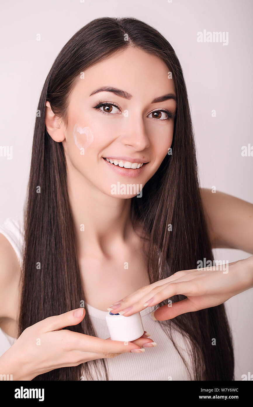Tratamiento facial. Mujer en el Salón de belleza. Aplicar crema cosmética. Una joven y bella mujer de aplicar la crema hidratante facial. Scine cuidado de la cara y las manos Foto de stock