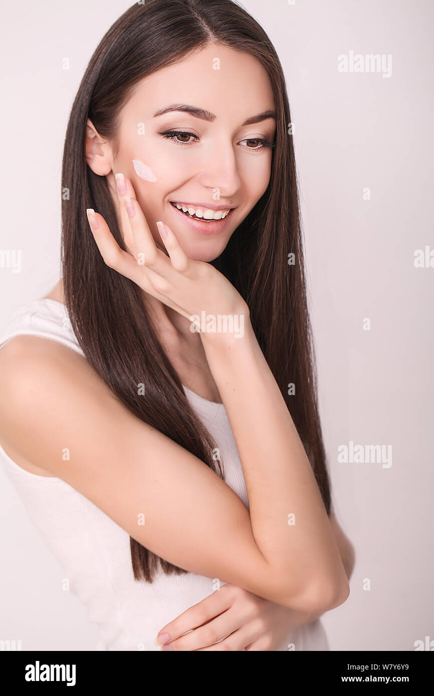 Aplicar crema cosmética. Una joven y bella mujer de aplicar la crema hidratante facial. Scine cuidado de la cara y las manos Foto de stock