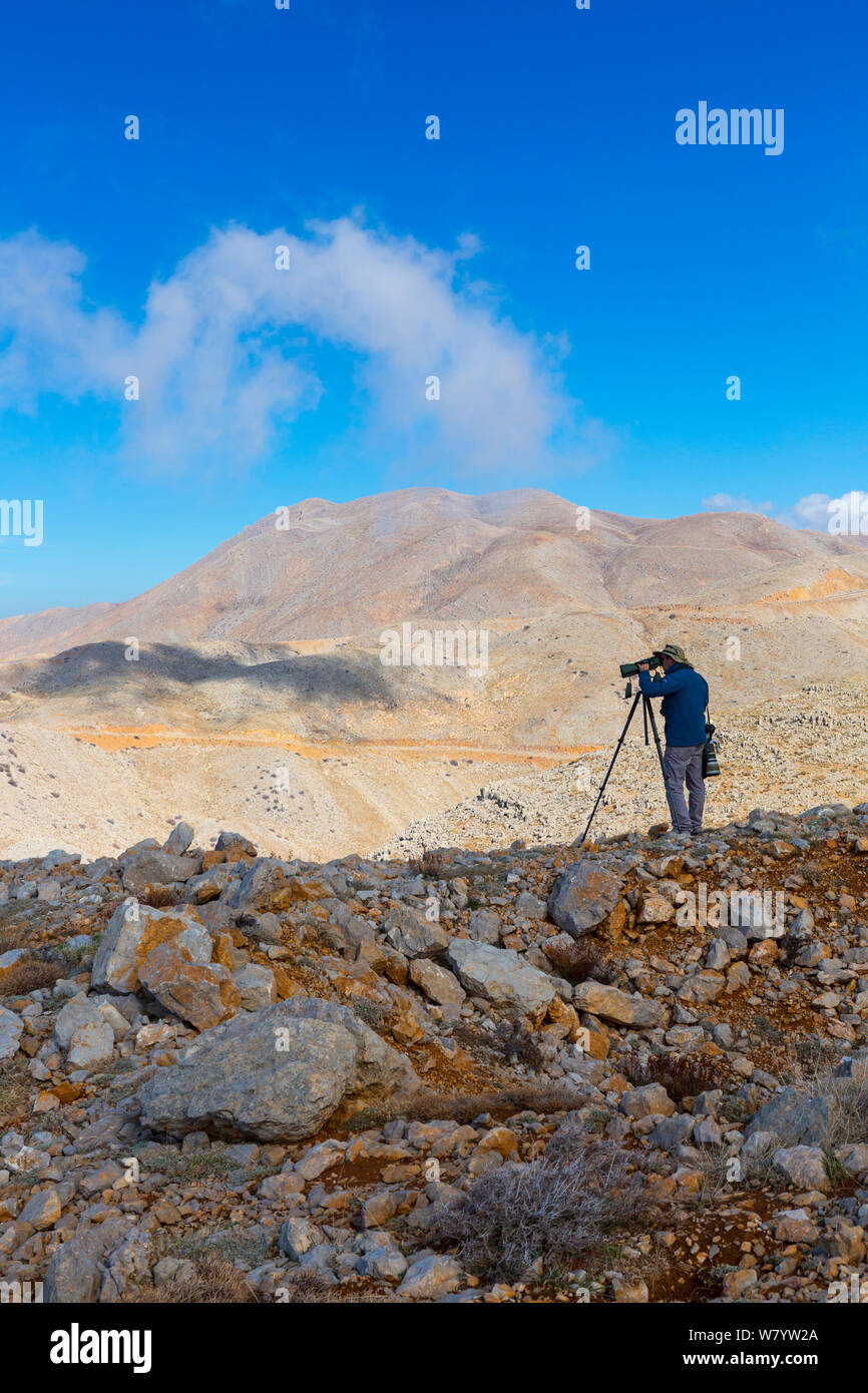 Birdwatcher mirando a través del telescopio, el Monte Hermon, Israel, noviembre de 2014. Foto de stock