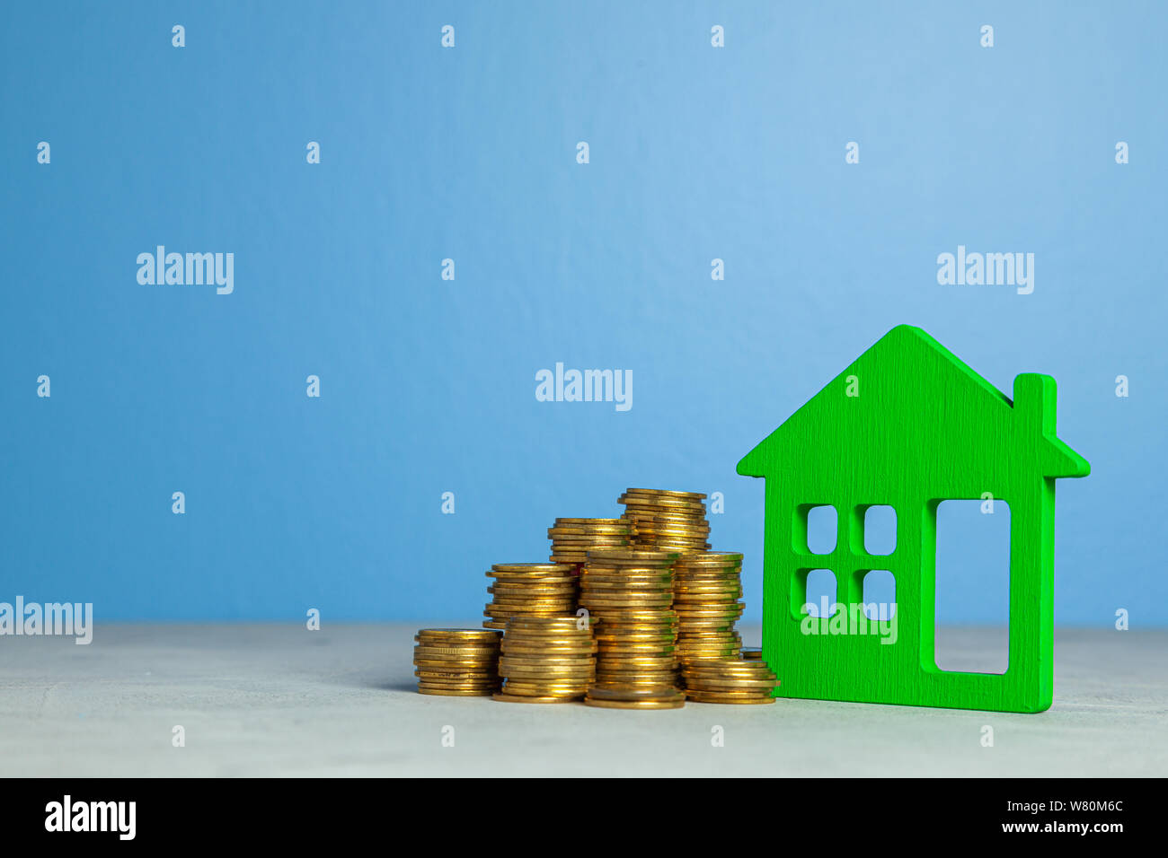Casa y pila de monedas. El concepto de la compra de casa o de seguros. Fondo azul. Espacio para el texto copia Foto de stock