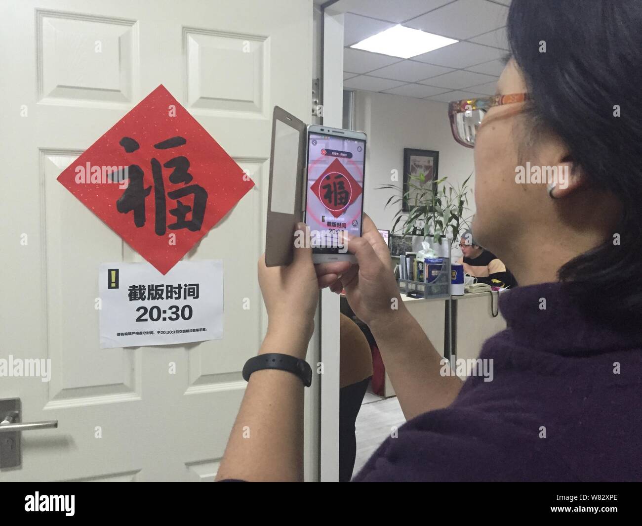 Una mujer china utiliza su smartphone para escanear el carácter chino "Fu", que significa "Suerte" en inglés, para reproducir un Pokemon Go-inspirado gam de realidad aumentada Foto de stock