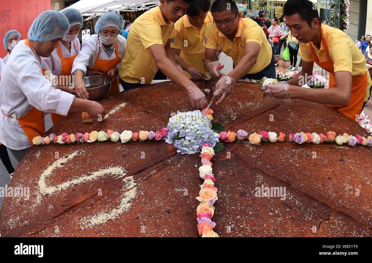 Los empleados de una empresa local de alimentos decoran el mooncake gigante con un diámetro de 2,4 metros durante un evento promocional para la próxima Mid-Autumn F Foto de stock