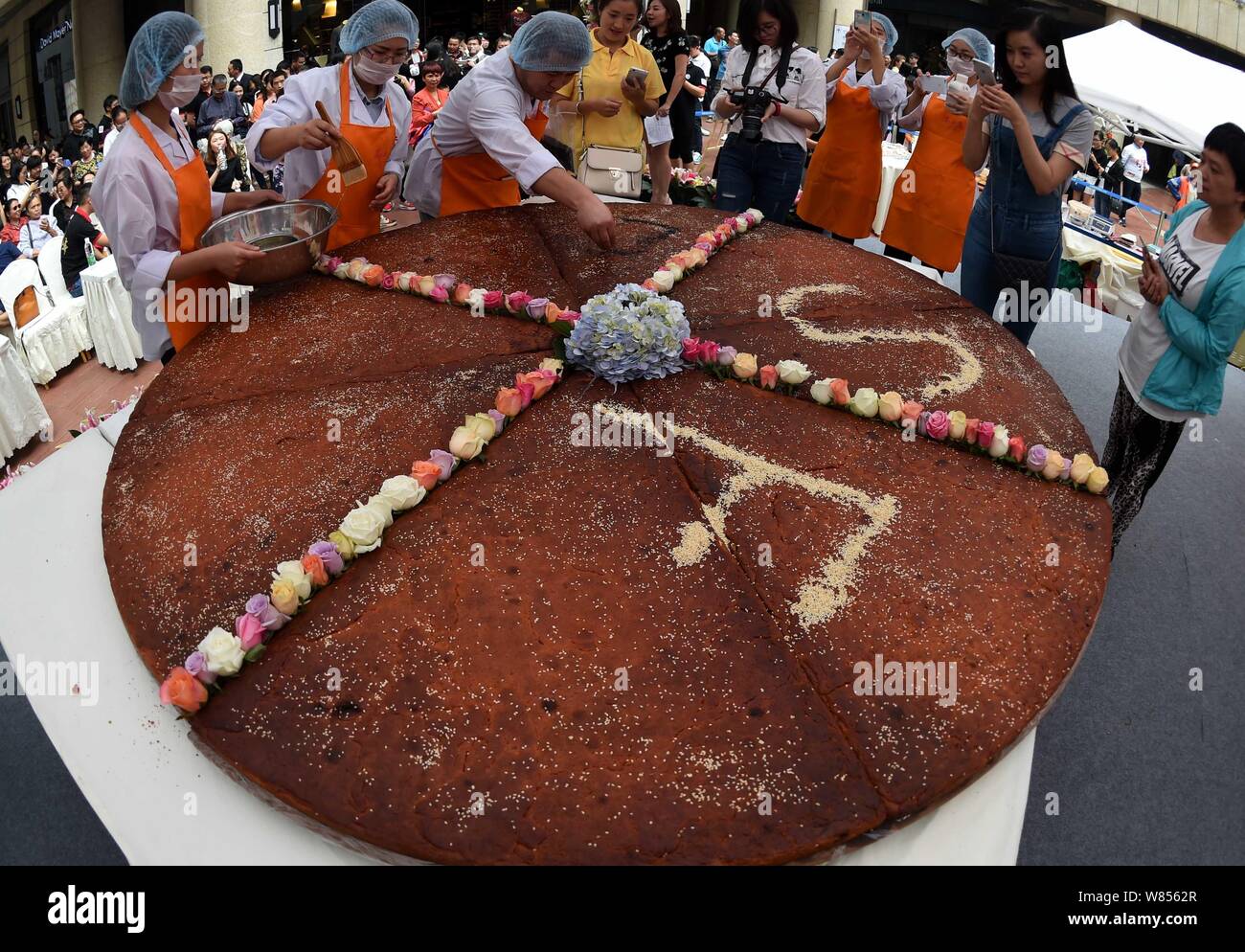 Un empleado de una empresa local de alimentos hace que los caracteres chinos con sésamo, que significa "Feliz Mid-Autumn Festival' en el mooncake gigante con un diámetro o Foto de stock