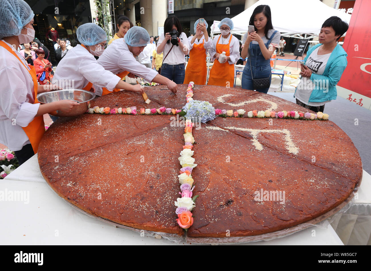 Los empleados de una empresa local de alimentos que los caracteres chinos en el mooncake gigante con un diámetro de 2,4 metros durante un acto promocional de la UPC Foto de stock