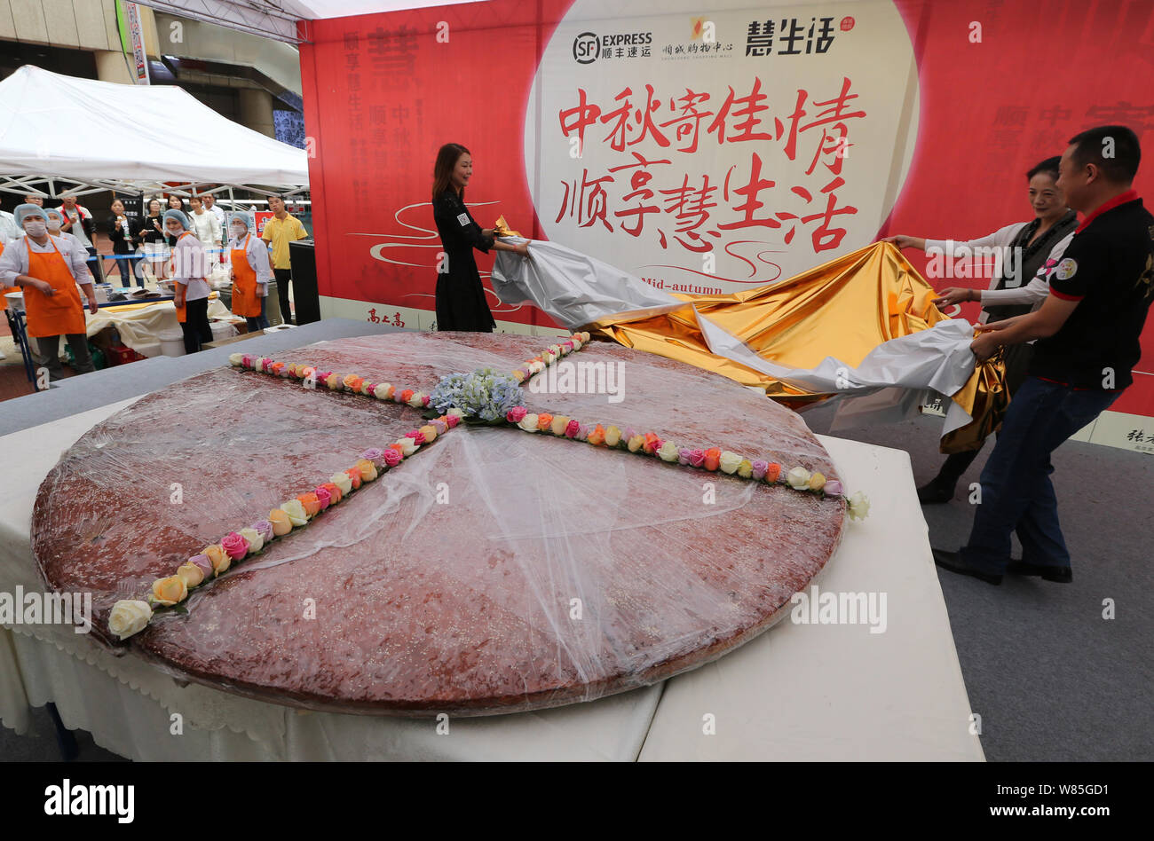 Los empleados de una empresa local de alimentos develar el mooncake gigante con un diámetro de 2,4 metros durante un evento promocional para la próxima Mid-Autumn Fes Foto de stock