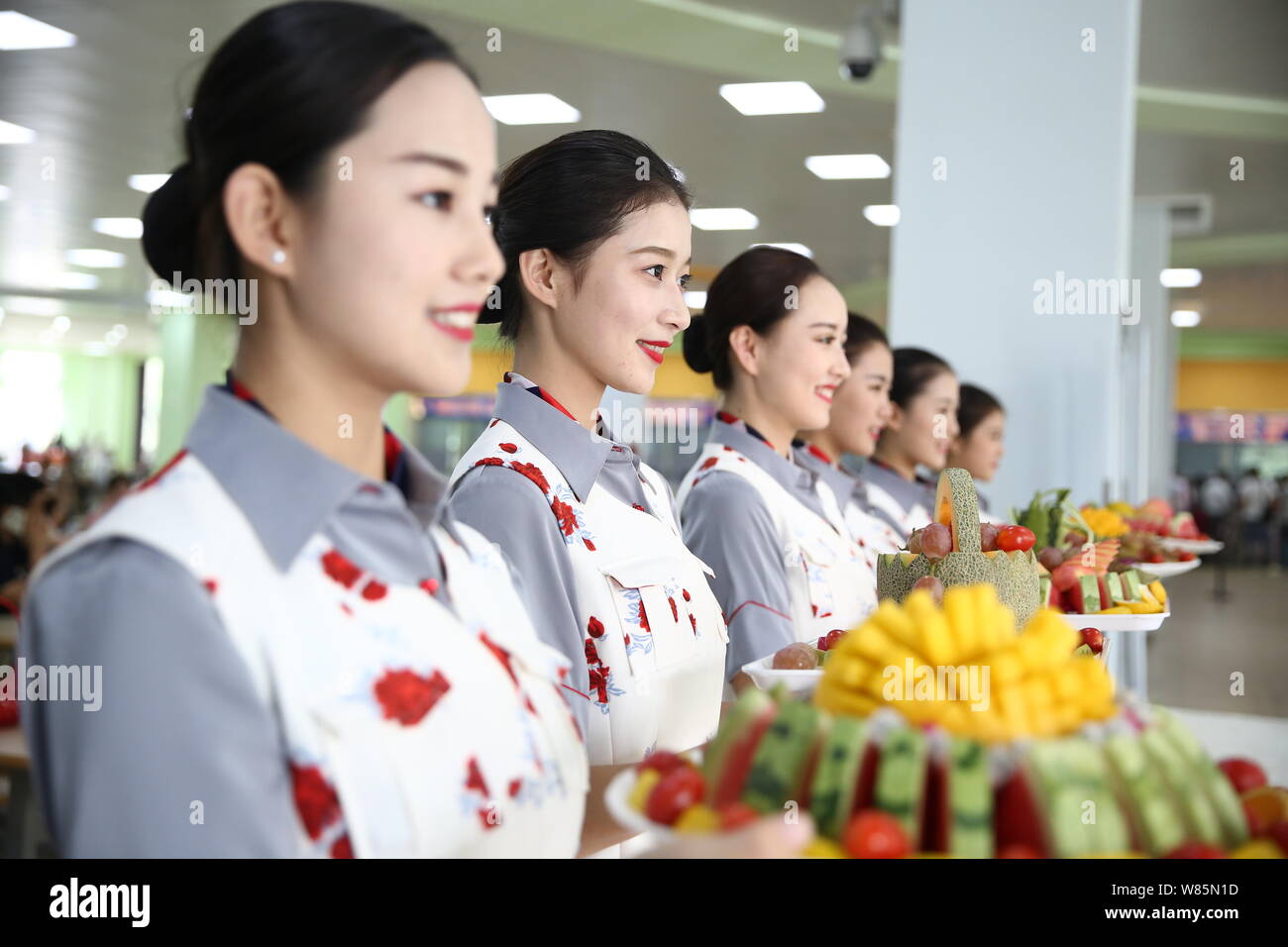 Los estudiantes universitarios vestidos con uniformes de azafatas de pie en  una fila para dar la bienvenida a los estudiantes de primer año y sus  padres en el suroeste de Sichuan de
