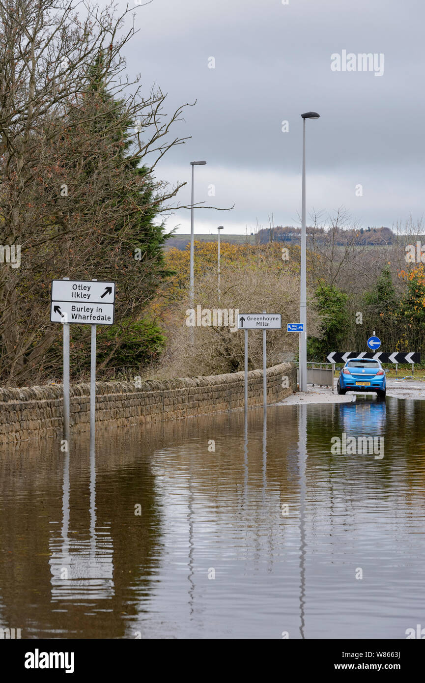 Inundaciones - camino inundado intransitables para el tráfico (coche aparcado) y profundos que la conducción de agua de inundaciones peligrosas -Burley de Wharfedale, en Yorkshire, Inglaterra, Reino Unido. Foto de stock