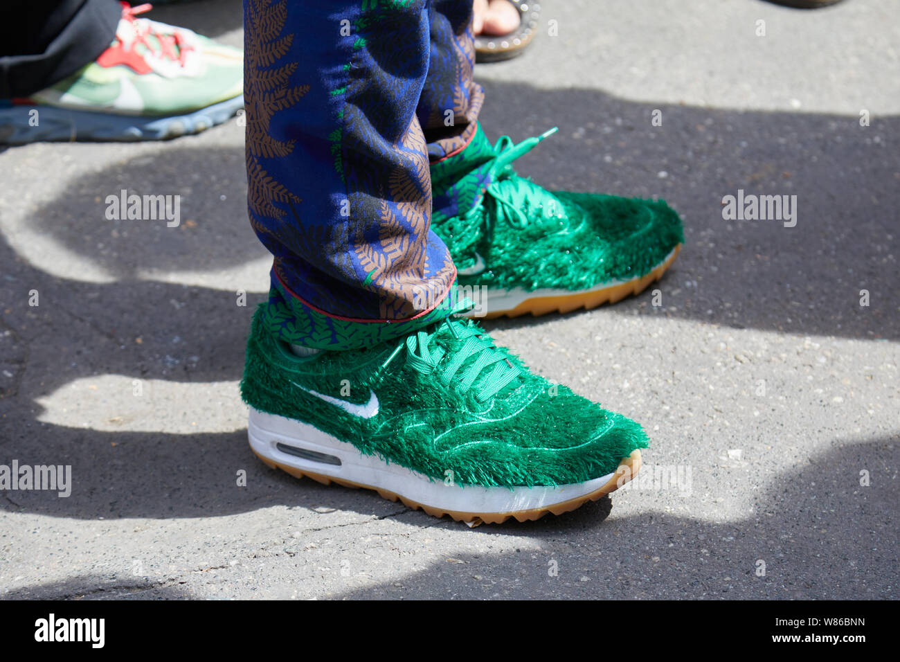 Milán, Italia - Junio 15, 2019: hombre con zapatillas Nike con pelaje verde antes Marni Fashion Show, la Semana de la moda de Milán street style Fotografía stock -