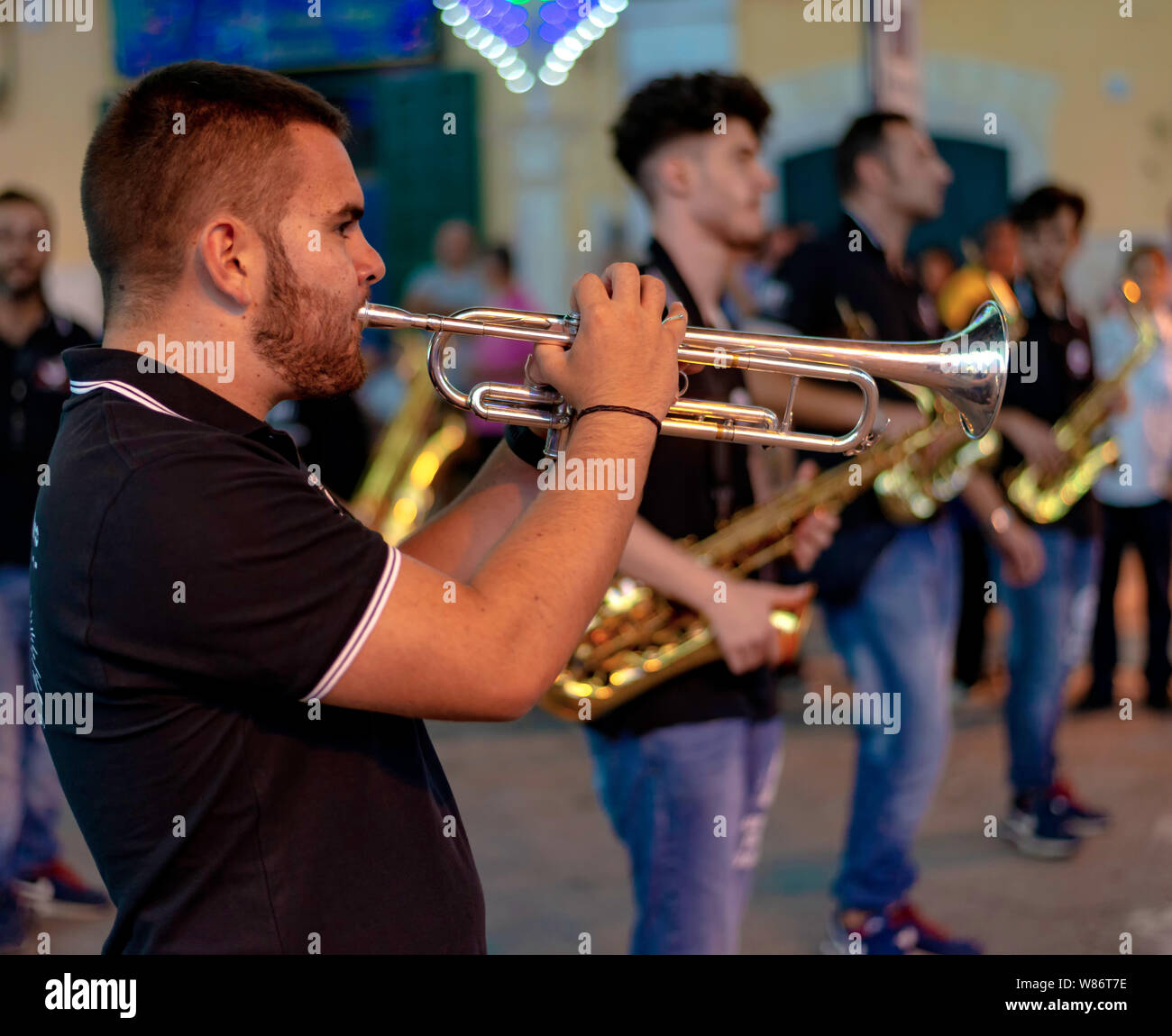 Modugno, Italia - 22 de septiembre de 2018: La plaza principal con luces montadas para la fiesta de la patrona. Destaca un músico tocando una trompeta Foto de stock