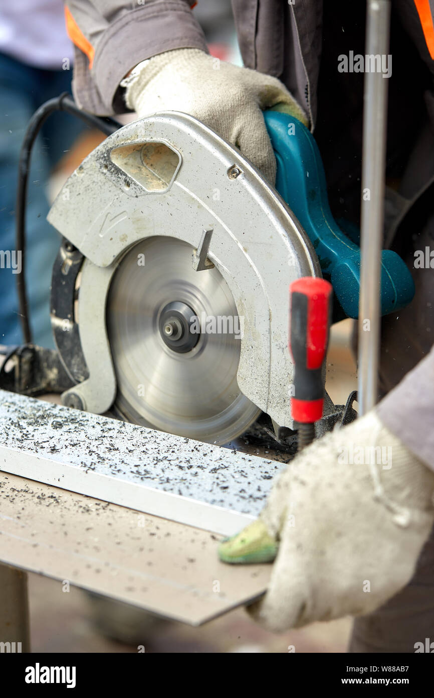 Un trabajador contratista de construcción mediante un gusano-driven sierra  circular de mano para cortar tableros y plástico. Concepto de construcción,  taller propio, la contratación de un Fotografía de stock - Alamy