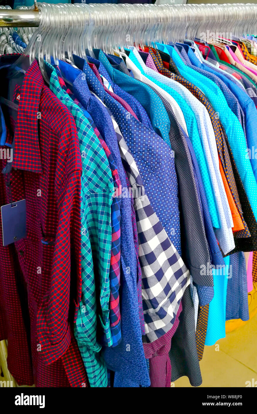 Las camisas cuelgan en el perchero en la tienda de ropa Fotografía de stock  - Alamy