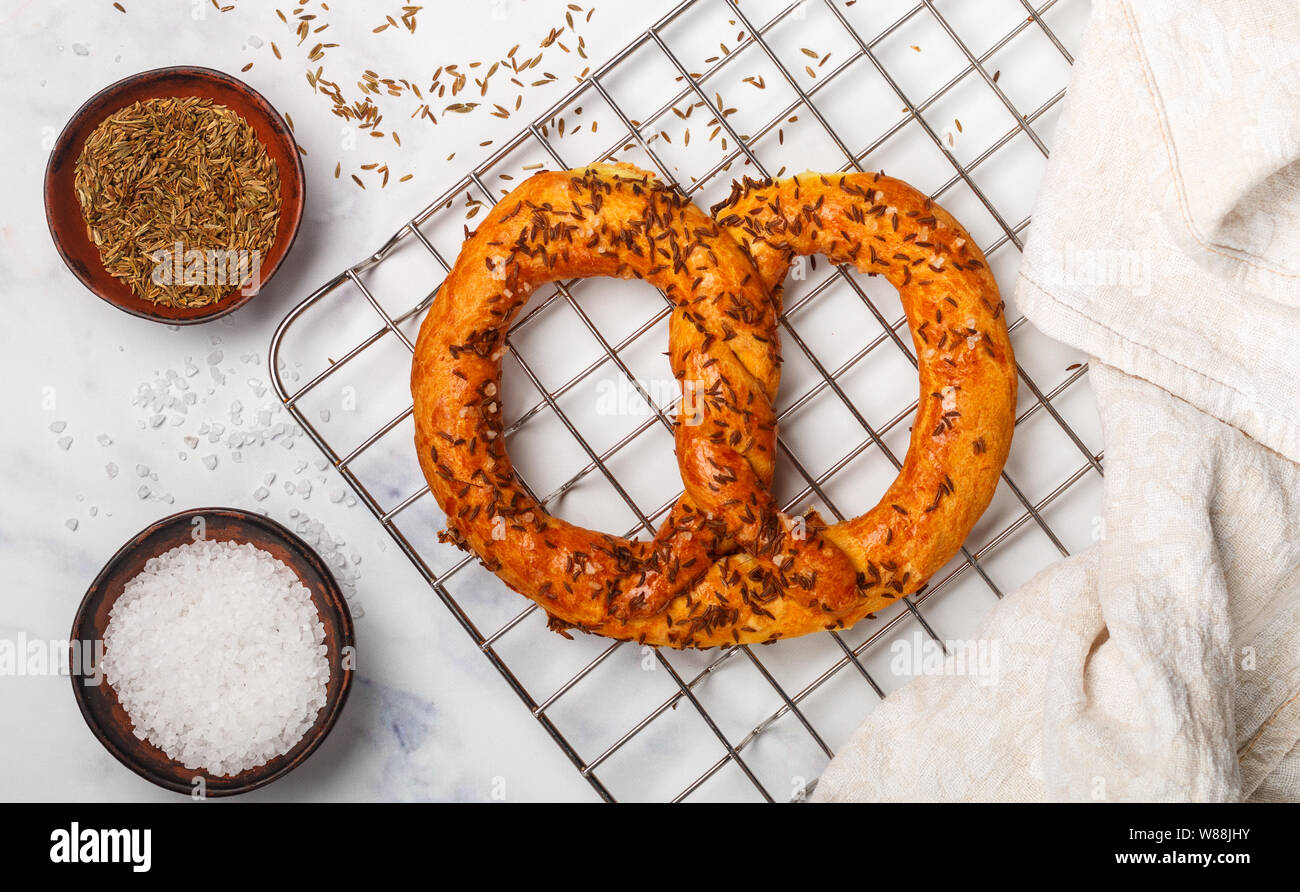 Pretzel recién horneados con sal gruesa y comino. Tentempiés Gourmet y los ingredientes en la mesa. Enfoque selectivo Foto de stock