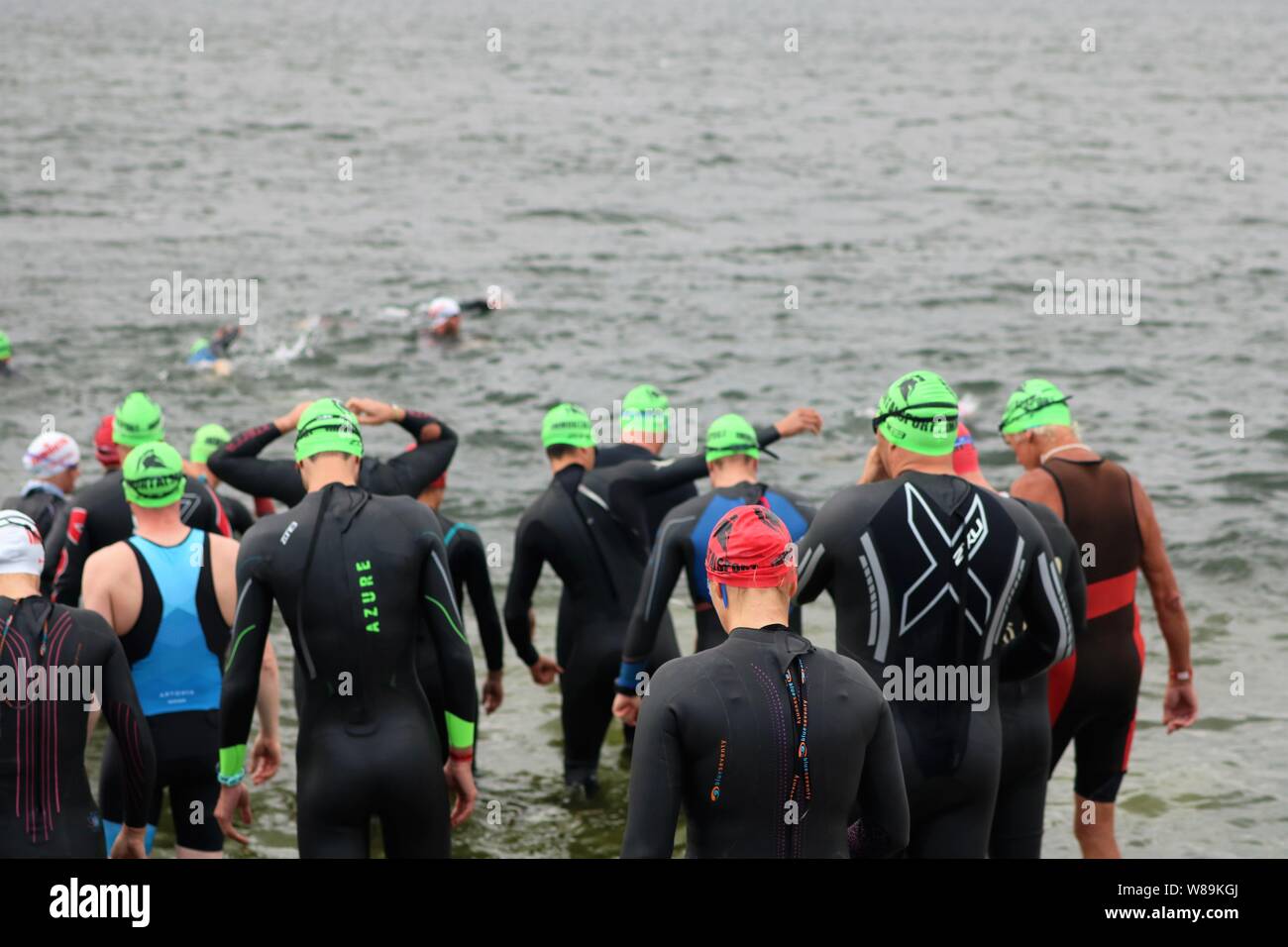 Las personas que toman parte en el sprint Farmoor Decathlon, comenzando con  el evento de natación Natación, vistiendo gorras y trajes de neopreno  Fotografía de stock - Alamy