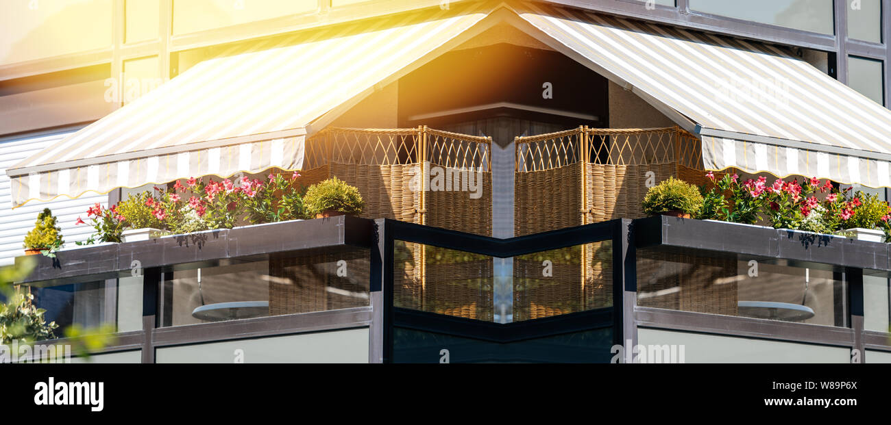 Largo balcón francés con hermosas flores cubiertas y toldos con rayos de  sol - protección durante la temporada de calor y radiación: La luz solar  flare Fotografía de stock - Alamy