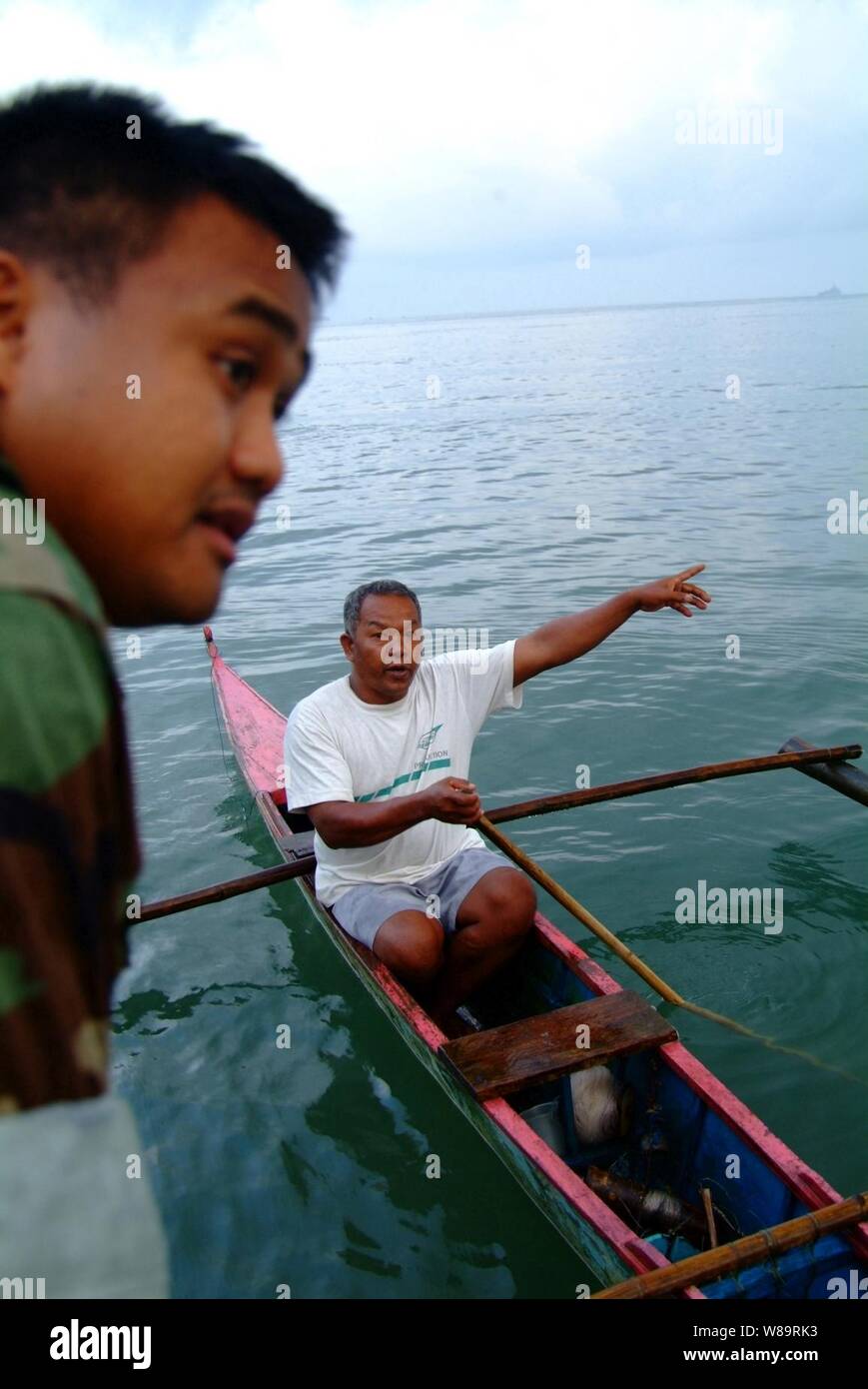 Marina de segunda clase de Suboficiales Christopher Arntzen habla con un local pescadores filipinos durante una encuesta de playa en la costa de Himbangan, Filipinas, el 20 de febrero, 2006. Arntzen y sus compañeros marineros del USS Harpers Ferry (LSD 49) busca lugares donde Landing Craft puede traer equipos de búsqueda y rescate y suministros de ayuda humanitaria para las víctimas del 17 de febrero de 2006, Guinsaugon, Filipinas alud de desastre. Foto de stock