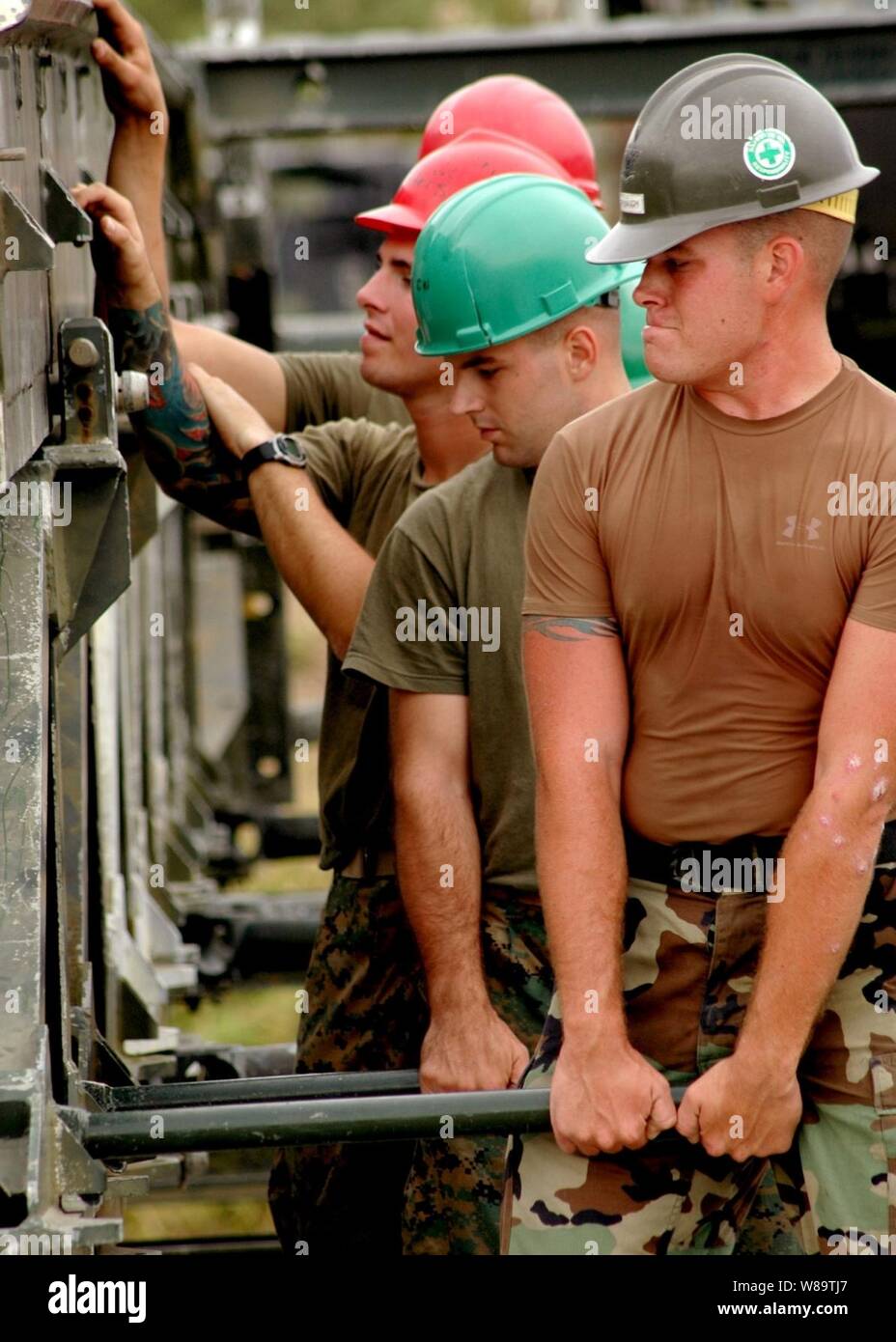 Marina Seabee Suboficiales Crubaugh marca de 3ª Clase (derecha) trabaja junto con los Marines del 9º Batallón de apoyo de ingenieros, 3er Grupo de Logística Marítima, III Fuerza Expedicionaria de la Marina, para armar una viga de medio puente durante un ejercicio de entrenamiento en el campamento de Hansen, Japón, el 14 de noviembre, 2006. Evoluciones de formación militar conjunta ayuda a promover las relaciones entre los Marines y Seabees en entornos de contingencia. Crubaugh se adjunta al batallón móvil de Construcción Naval 1. Foto de stock
