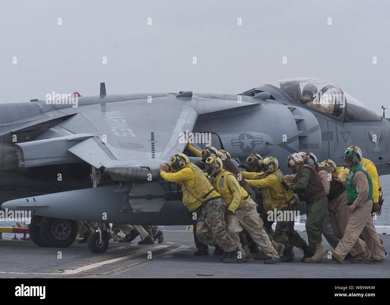 Los miembros de las tripulaciones de la Marina de EE.UU. Presione un AV-8B Harrier avión sobre una aeronave ascensor a bordo del buque de asalto anfibio de la clase Wasp USS Essex (LHD 2) El 29 de abril de 2008. El Essex es el barco de plomo de un forward ñdeployed expedicionaria de EE.UU. Grupo de ataque. Foto de stock