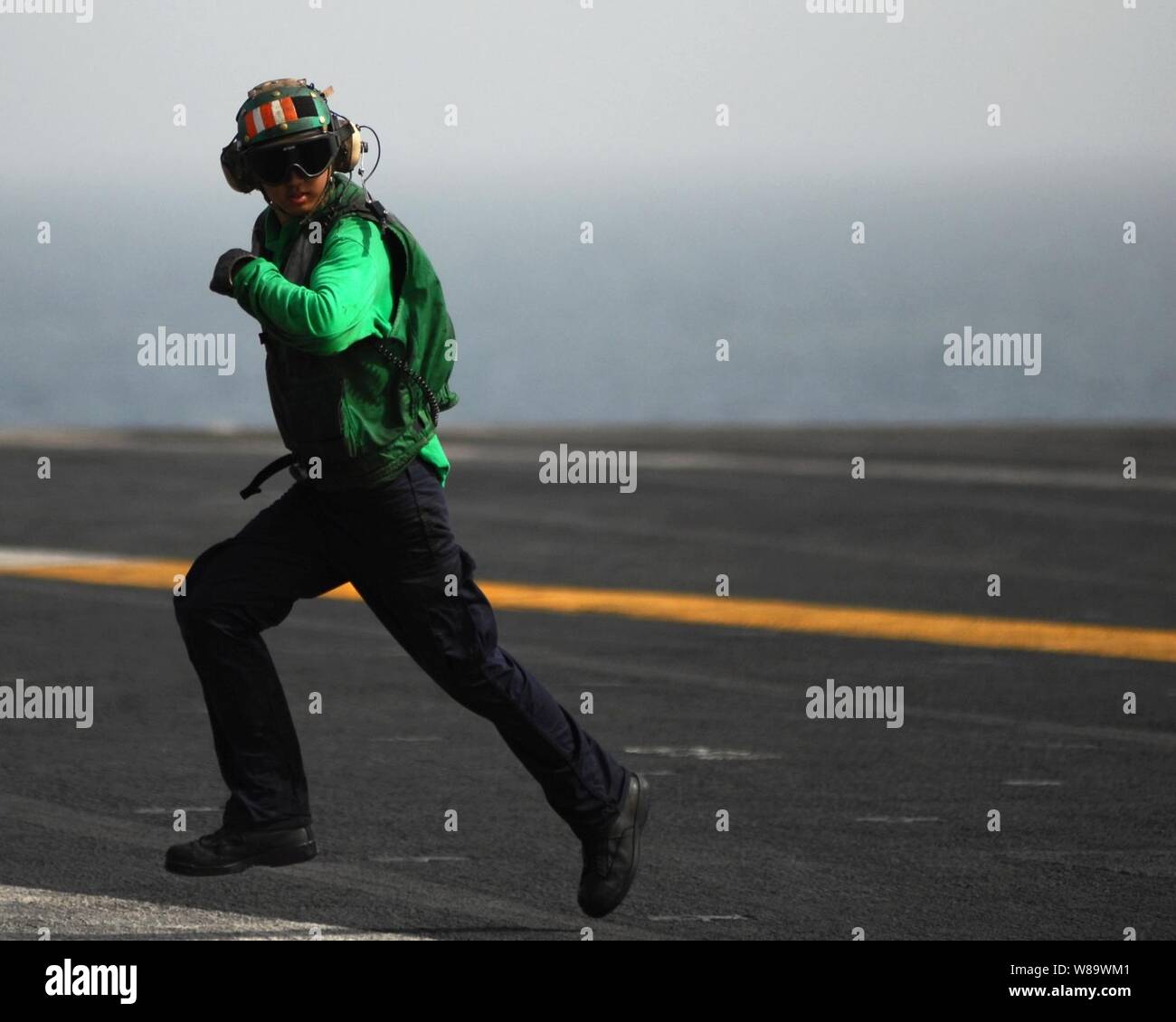 La aviación de la Marina de los EE.UU Boatswain's Mate Suboficiales Michael Kwon sprints de 3ª clase de regreso a través de la zona de aterrizaje después de comprobar el estado de un cable durante la detención de aeronaves de ala fija en operaciones de recuperación a bordo de la clase Nimitz portaaviones USS Abraham Lincoln (CVN 72) mientras se llevan a cabo en el Golfo Pérsico el 20 de mayo de 2008. El Lincoln está desplegado en la Marina de los EE.UU. 5ª Flota área de responsabilidad para apoyar operaciones de seguridad marítima. Foto de stock
