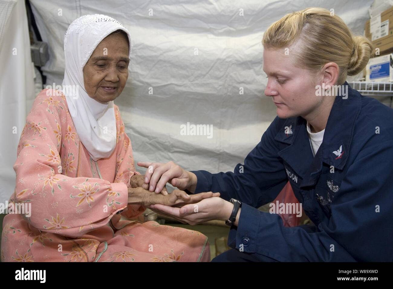 Marina de los EE.UU. 3ª clase Suboficiales Brittany Robinson, de la USS McCampbell (DDG 85), examina una patientís mano en el Equipo de Respuesta Rápida de la asistencia humanitaria instalaciones médicas en Padang, Indonesia, el 12 de octubre, 2009. Los marineros de la McCampbell y el dock buque anfibio de transporte USS Denver LPD (9) voluntariamente su tiempo en el hospital, que presta atención médica a los residentes de West Sumatra tras dos terremotos. La fuerza anfibia séptima Flota está dirigiendo el esfuerzo militar de Estados Unidos en respuesta a una solicitud del Gobierno de Indonesia. Foto de stock
