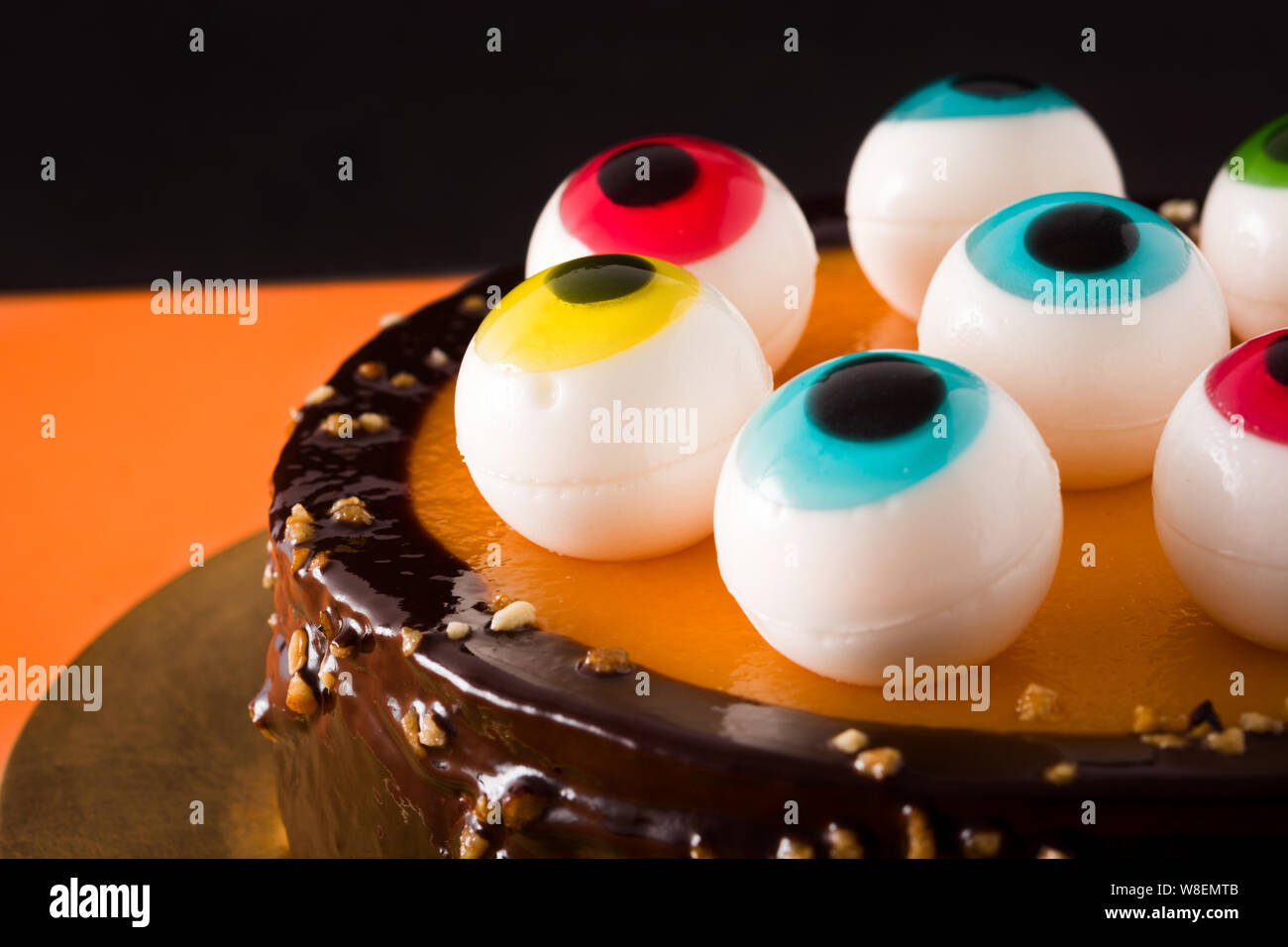 Pastel de Halloween con dulces ojos de decoración en naranja y el negro  como color de fondo Fotografía de stock - Alamy