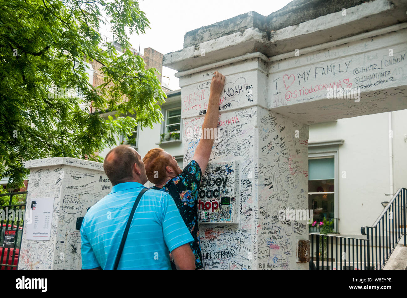 Dos turistas escribir graffiti en el muro exterior de Abbey Road Studios de Londres. Foto de stock